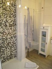 Die Dusche mit Echtglaswand, an der kurzen Seite mit Duschvorhang