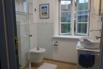 Das Bad mit Handwaschbecken, Toilette, groem Fenster (Plissee als Sichtschutz) und ...